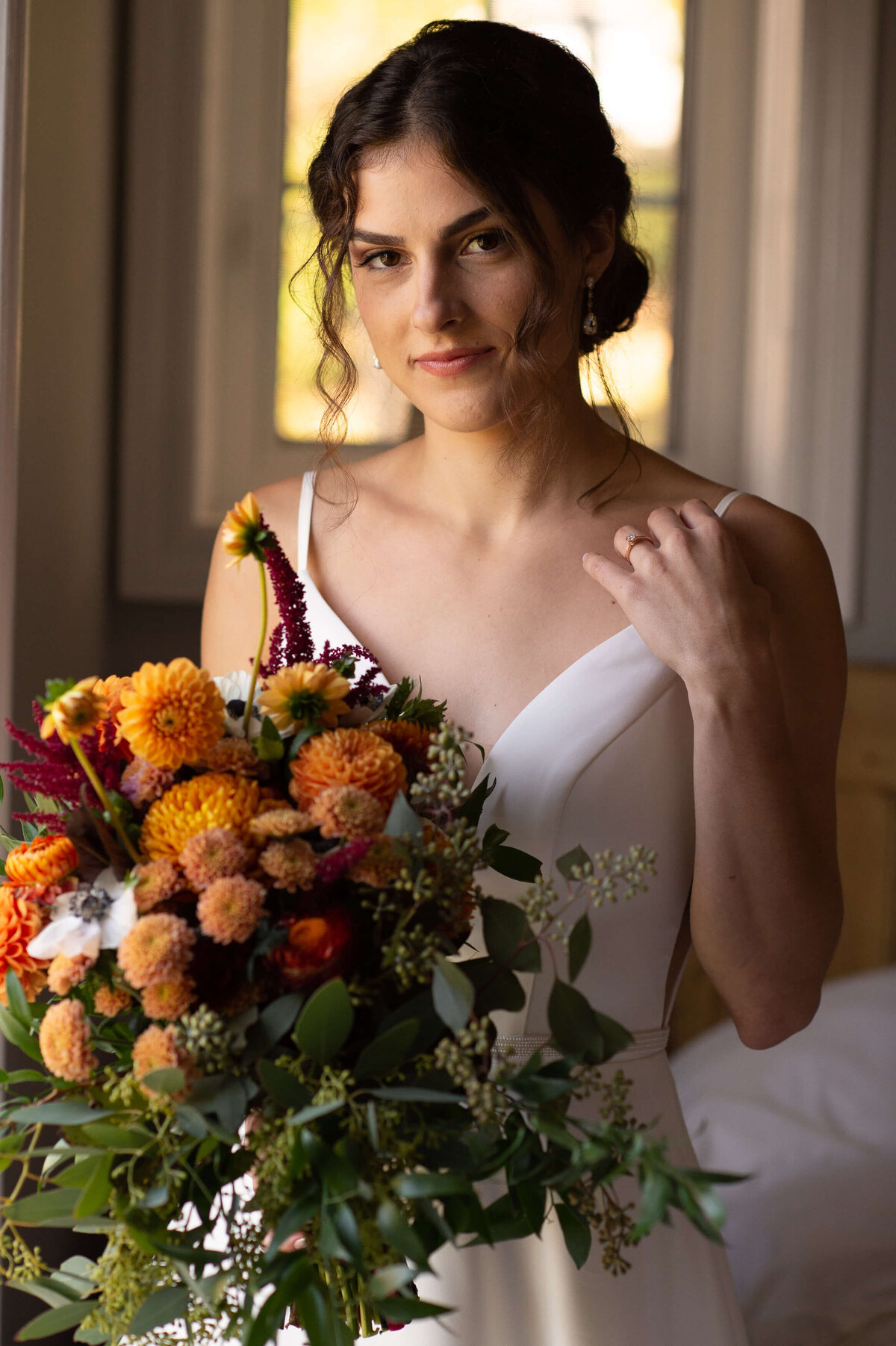 a moody bridal portrait of a bride holding a fall coloured wedding bouquet as she gets ready for her Strathmere wedding in Ottawa.  Captured by Ottawa wedding photographer JEMMAN Photography