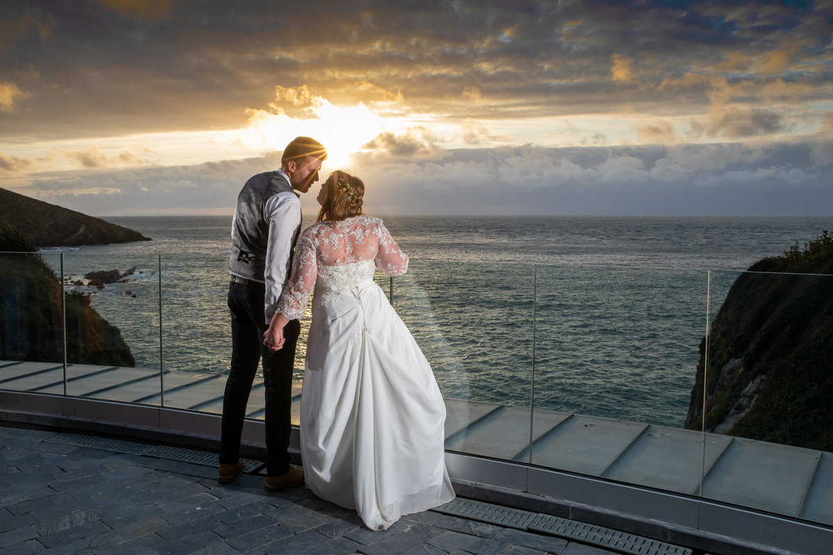 Married couple sharing a kiss on the roof terrace at Tunnels Beaches in Devon at sunset