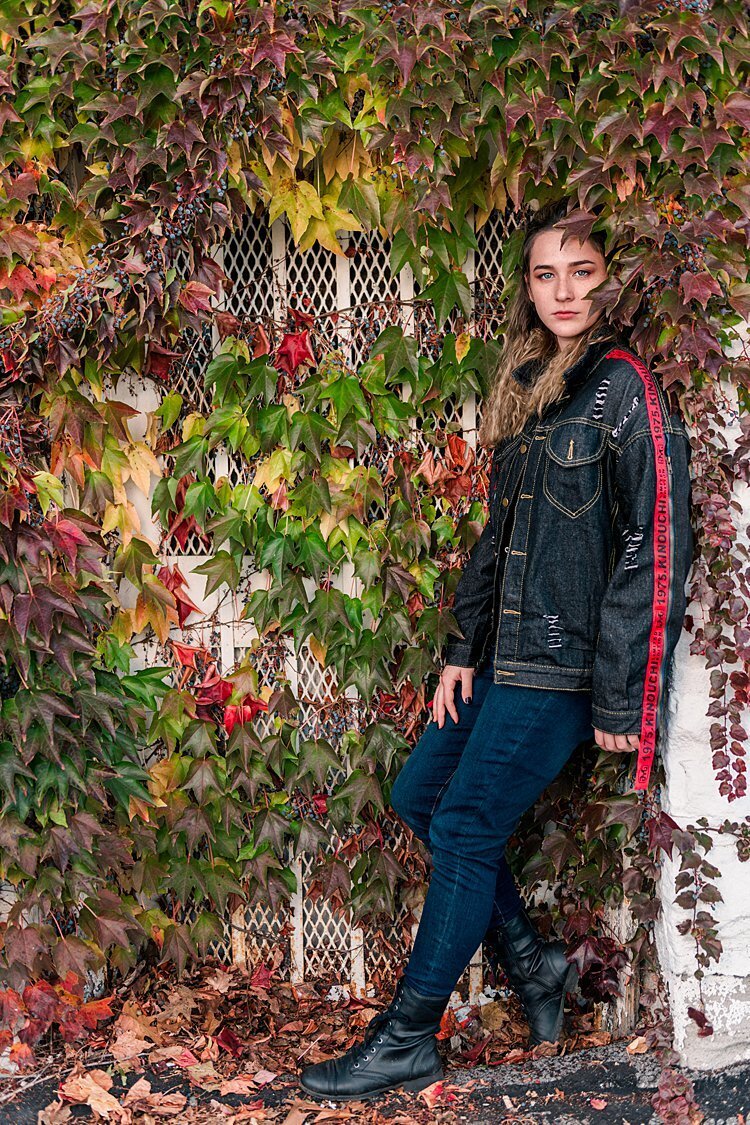 High school senior girl leaning against doorway among wall of ivy
