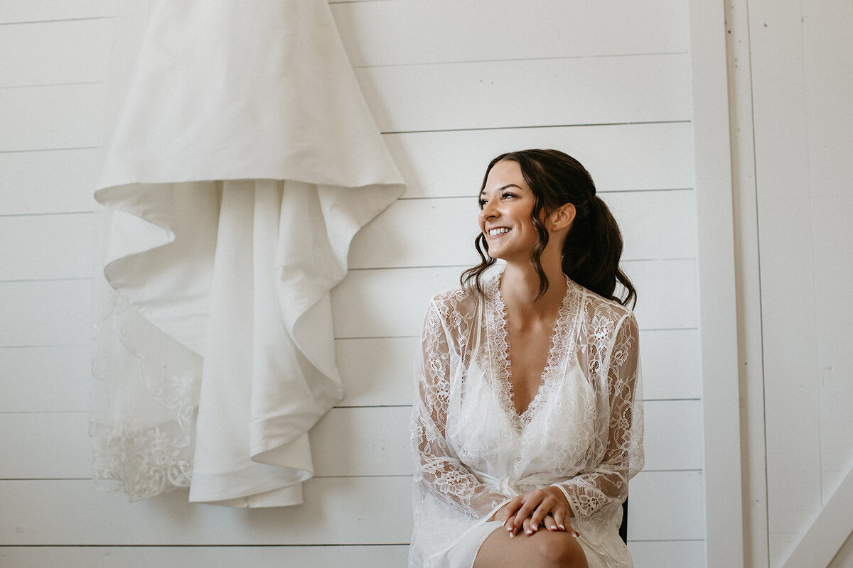 Bride in lace robe with soft waves and natural glam makeup in Madison, WI.