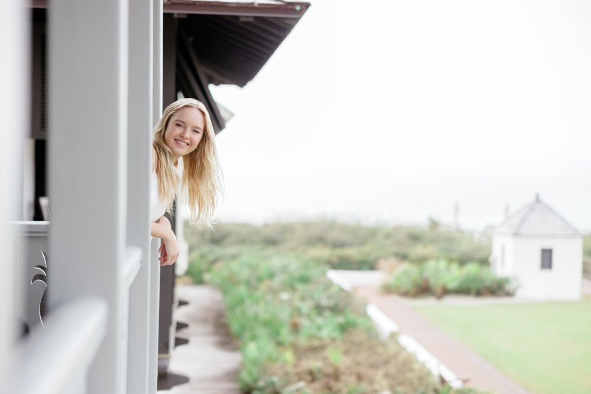 A girl smiling and leaning out a window