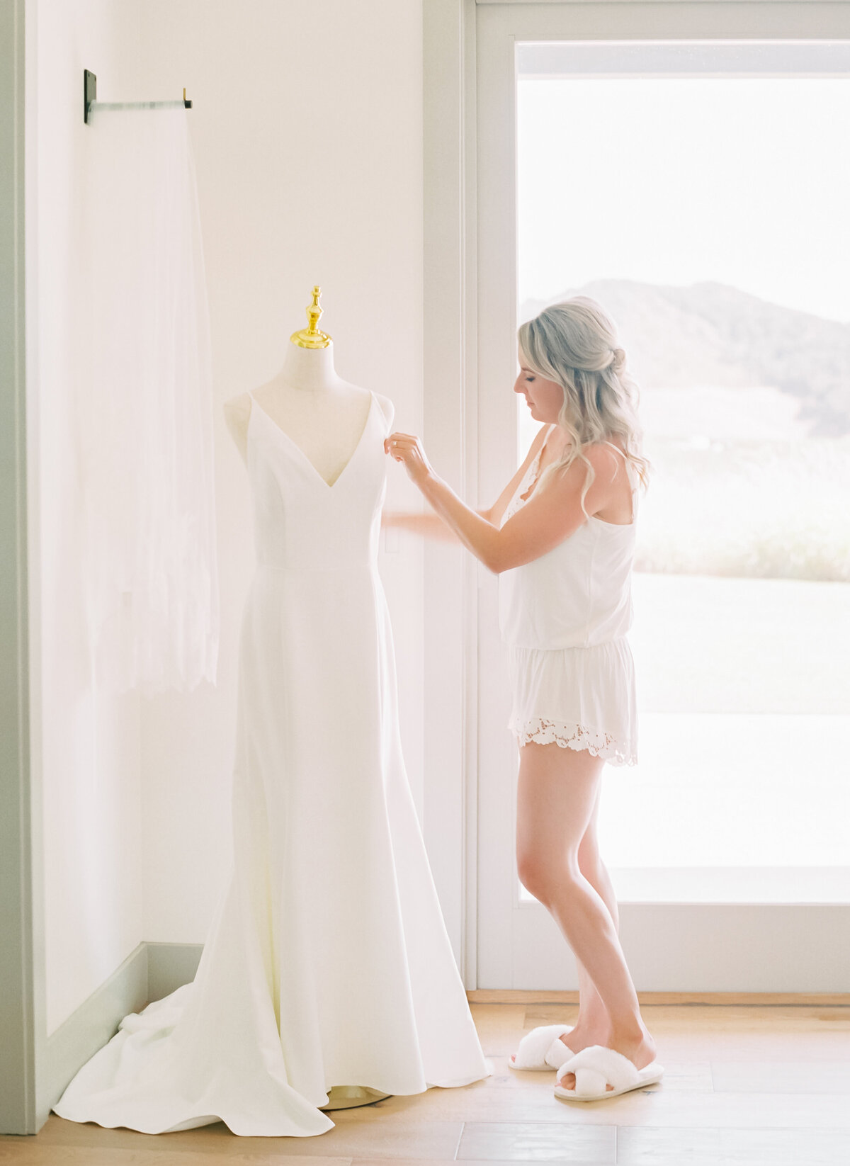 bride admiring dress on mannequin