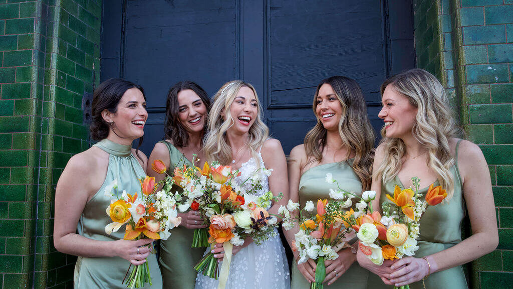 Bride and bridesmaids in green sating dresses laughing