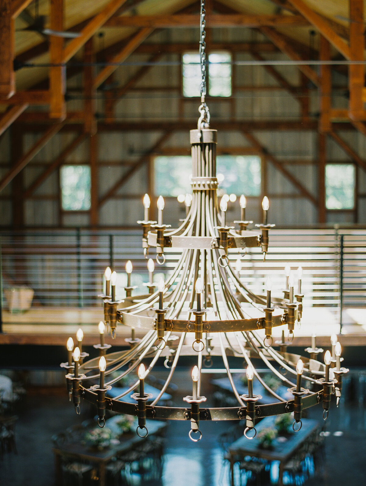 Large chandelier hanging from the ceiling of the Groom in a pink jacket and bride in an elegant dress posing for a portrait at Wildflower On Watts wedding venue