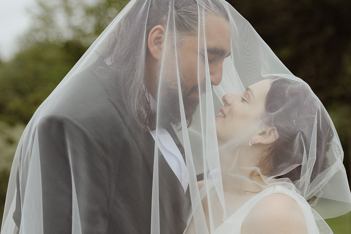 bride and groom pose for photos under veil on wedding day in lancster pa