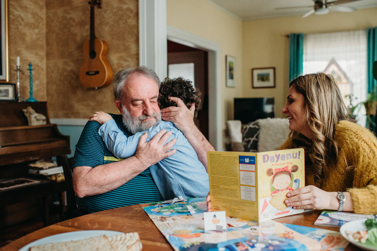 boy hugs grandpa while reading a story at kitchen table