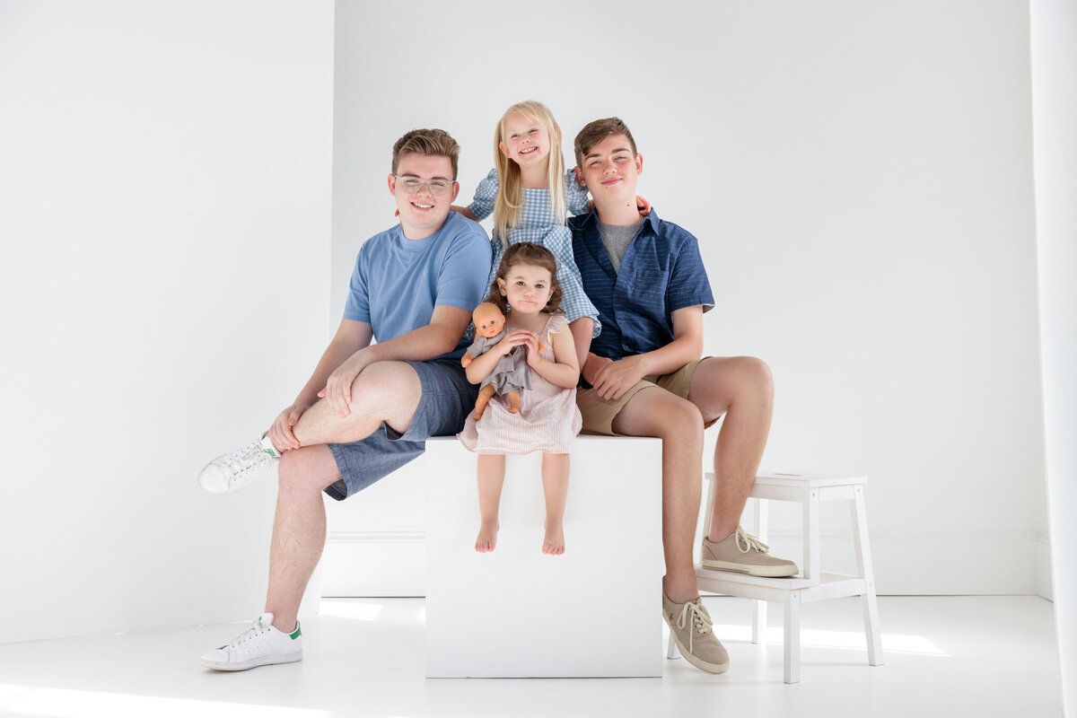Four Children seated in an all-white photo studio.