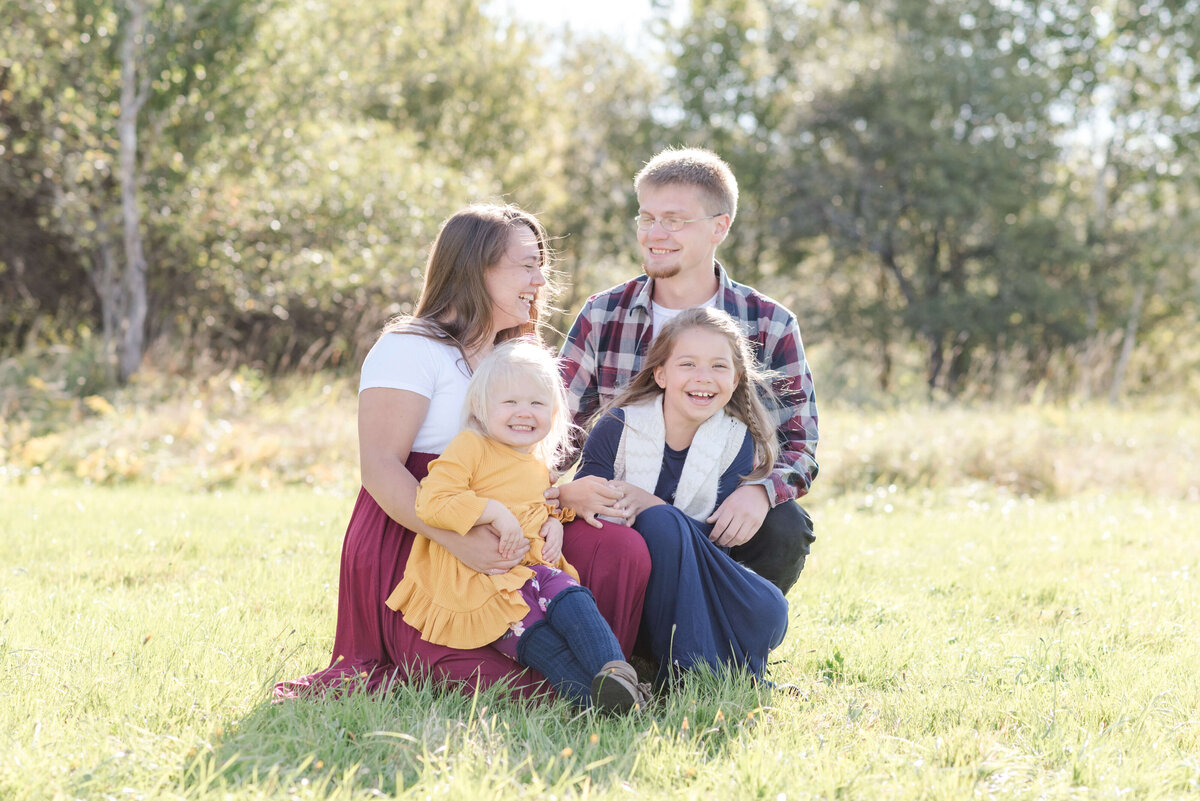 Family of 4 sitting in the grass for Fall  photos, at Tempson Barn, Lyndonville, VT