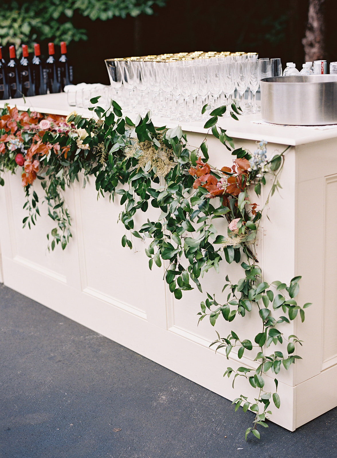 Floral installation on the front of the bar with smilax vines, copper beech, hops, and wildflowers. RT Lodge wedding and corporate event florist.