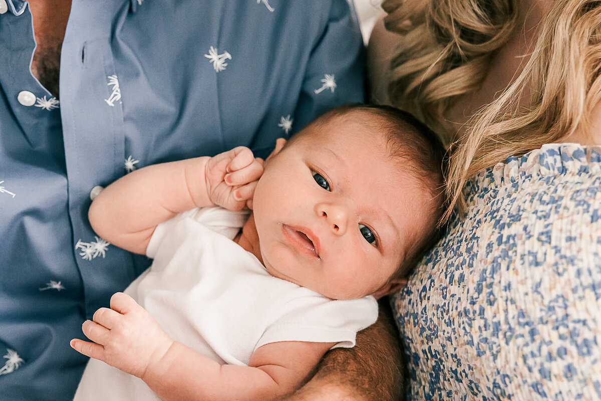 Baby boy looking at camera with hand up to ear