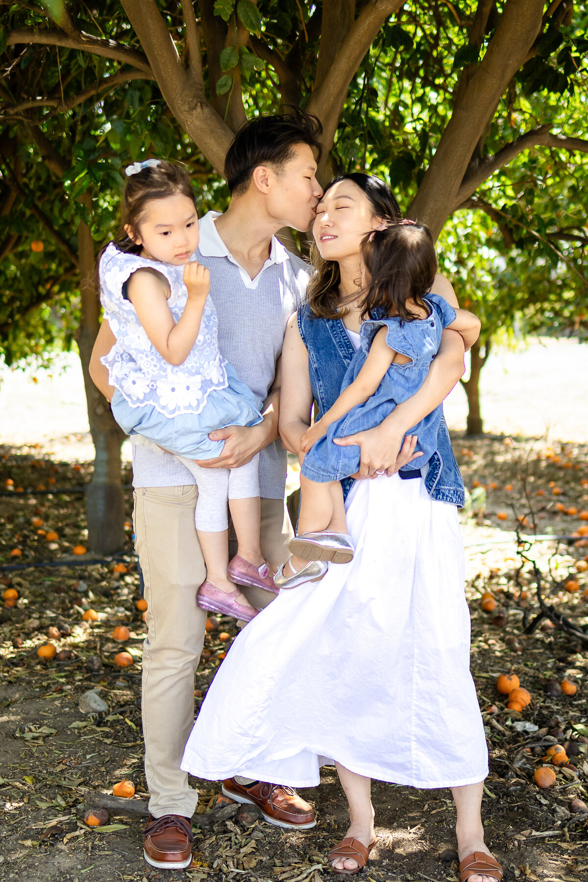 Mom and Dad sharing a warm hug with her two daughters children during a playful outdoor session – lifestyle family photography by Ellobelle Photography, San Francisco Peninsula