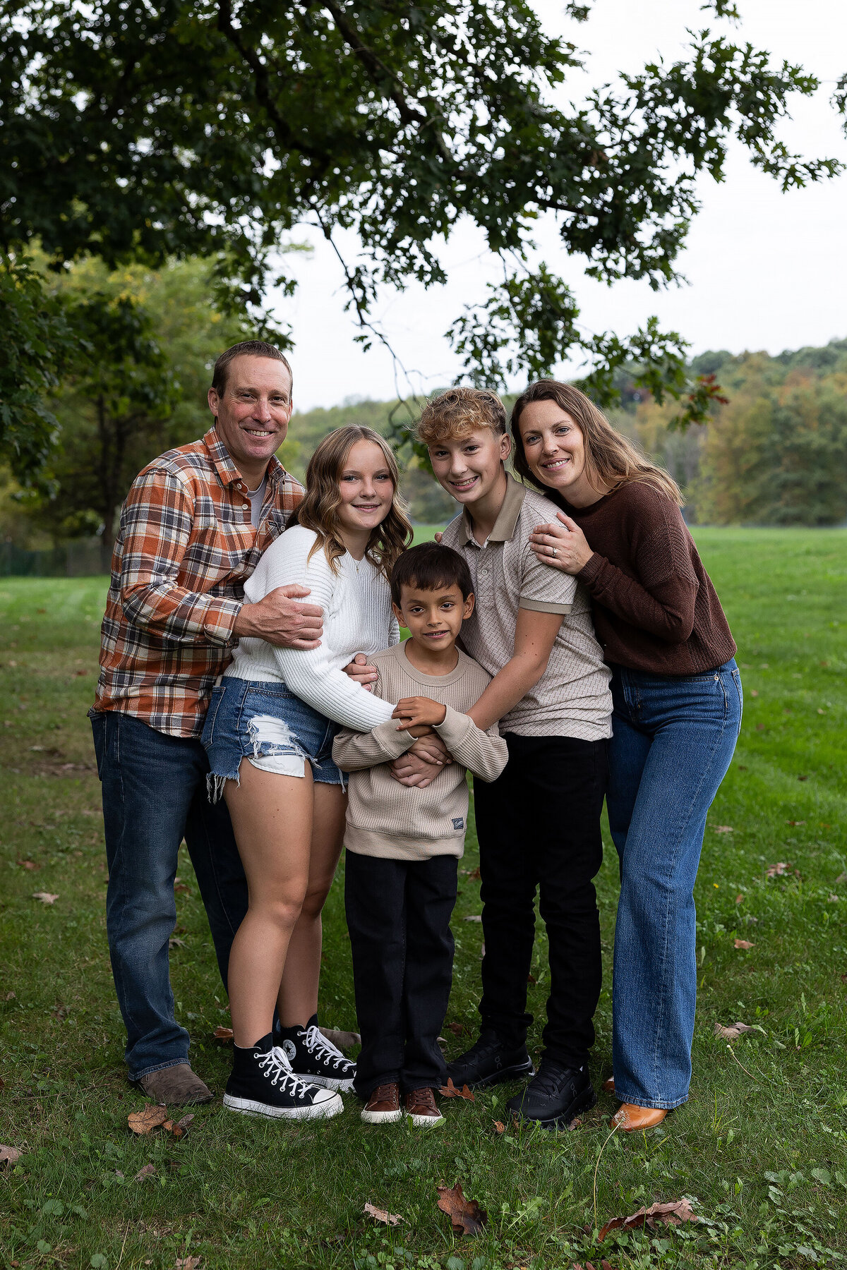 FamilystandingholdingeachotherinafieldinGreensburgpa