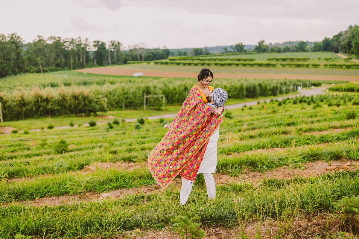 Groom picking up the bride during the engagement session in punjabi themed attire