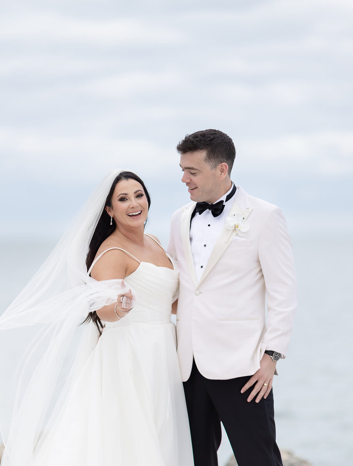 The bride gently holding the groom’s arm while smiling during their waterfront wedding at Ocean Reef in Key Largo, captured by Claudia Amalia Photography.