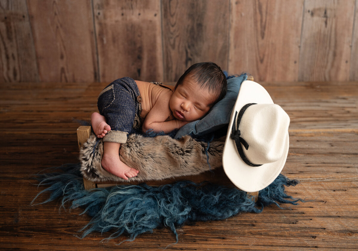 fort worth newborn boy in a bed with a cowboy hat