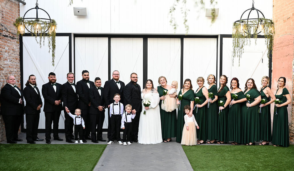 A bride and groom standing with their wedding parties on either side of them.