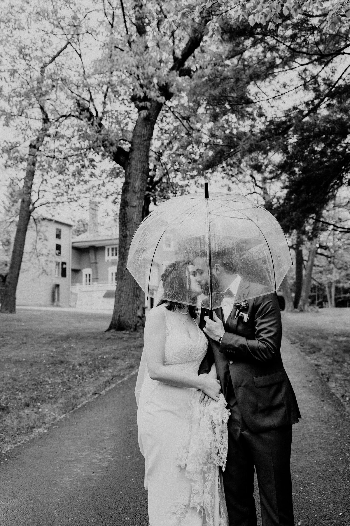 The bride and groom kissing under a transparent umbrella