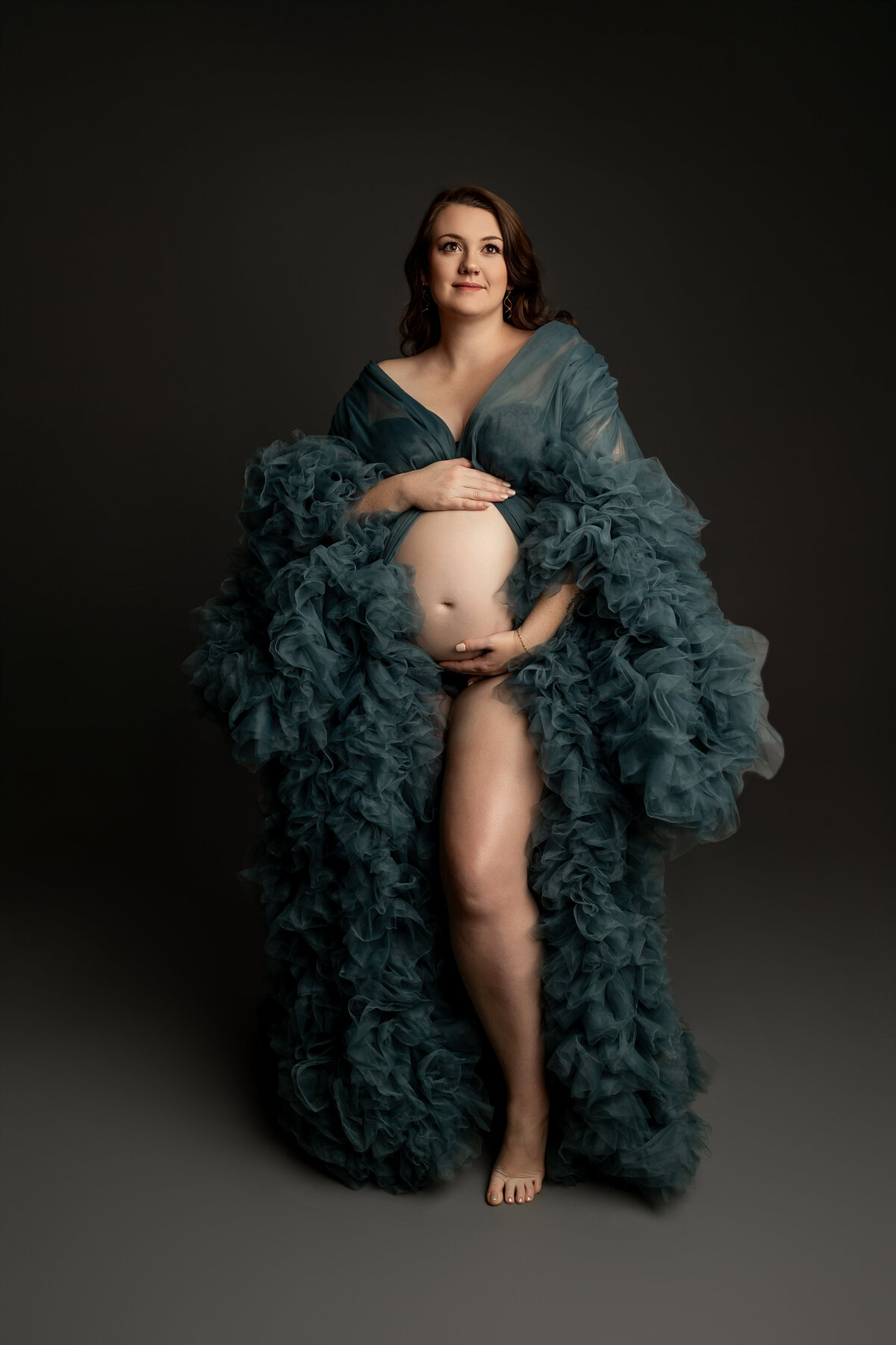 The expectant mother stands with a serene expression, capturing the beauty and anticipation of her pregnancy. Captured by Inland Empire maternity photographer Kaitlyn Dawn Photography.