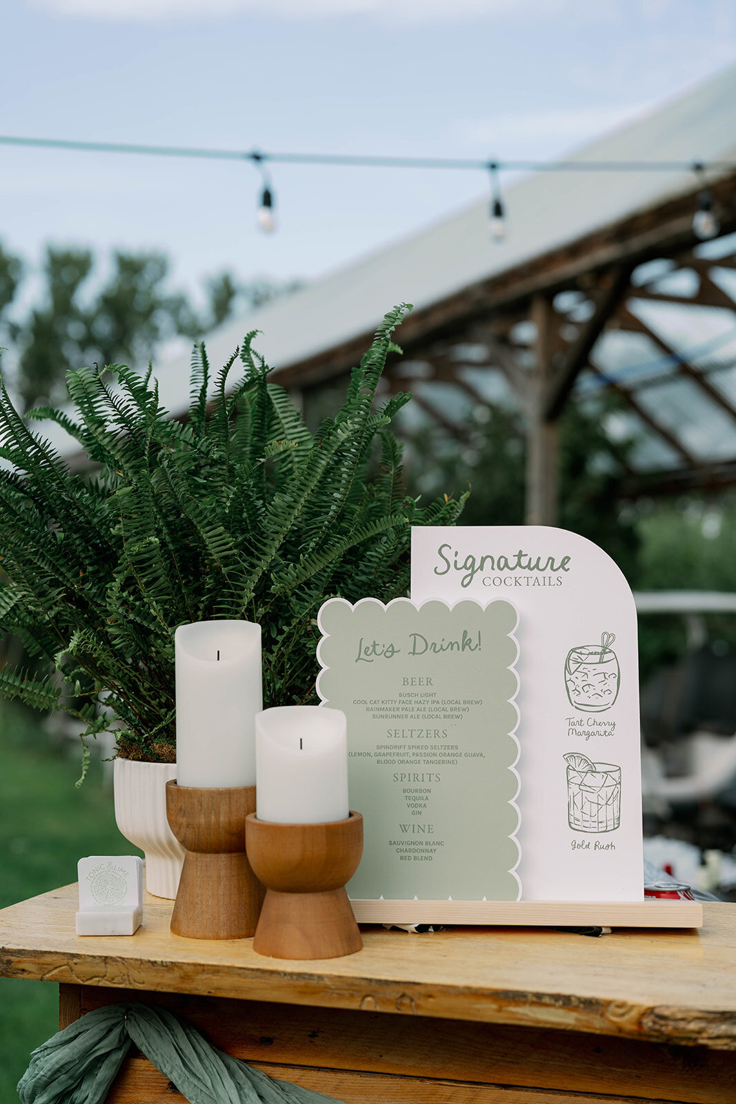 Close-up of a sage green scalloped drink menu—a stylish signage detail from a Cherry Barn wedding in Frankfort MI.