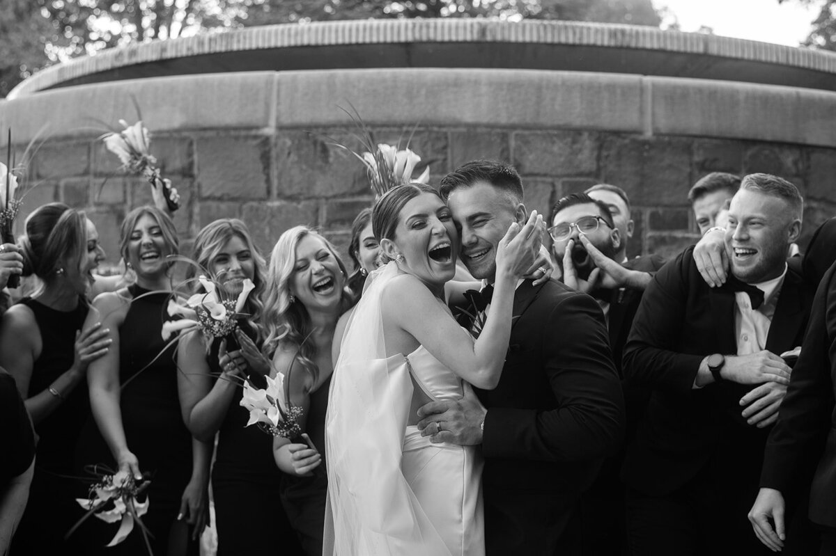 birde and groom laugh with wedding party cheering around them prior to their new haven lawn club wedding cait fletcher photography