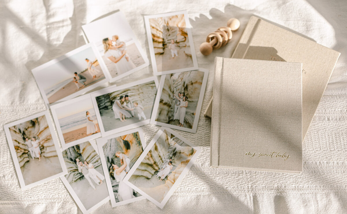 Assortment of printed family photos, next to artisan photo albums and wooden baby toy