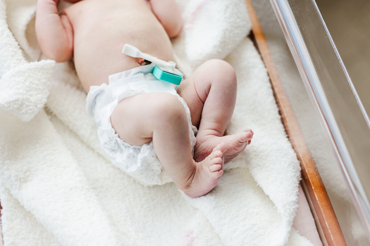 close up of newborn baby's feet lying on soft white blanket in hospital crib