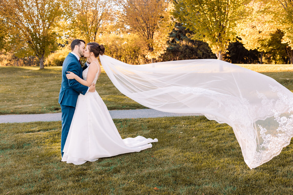 Bride and groom kiss as the brides veil flies behind her 