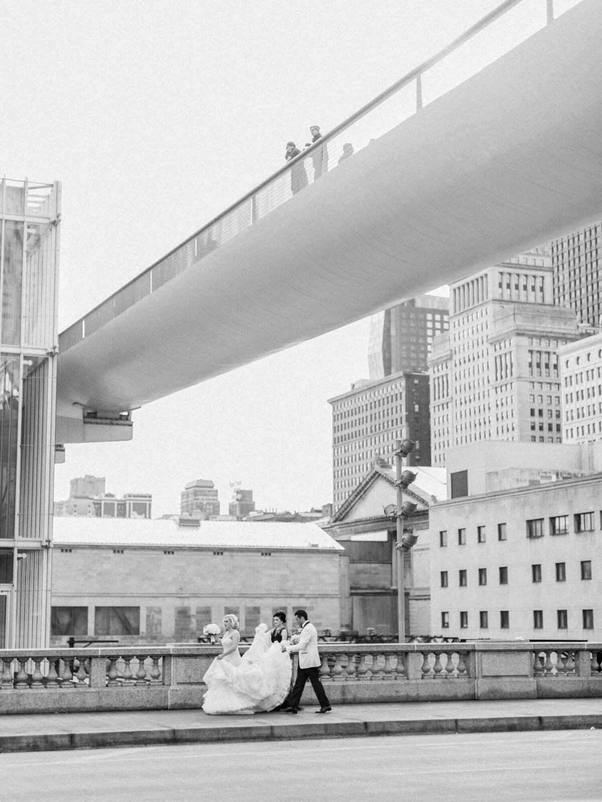 A black and white candid wedding photo of a bride and groom walking down the sidewalk of downtown Chicago