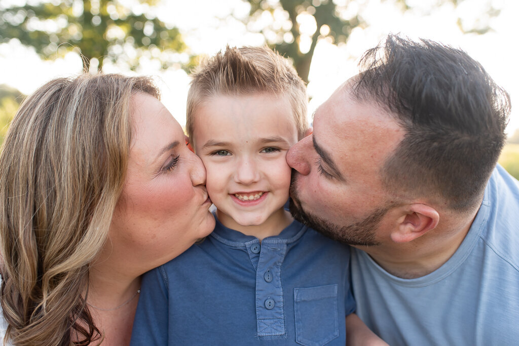 Parents kissing son's face in field