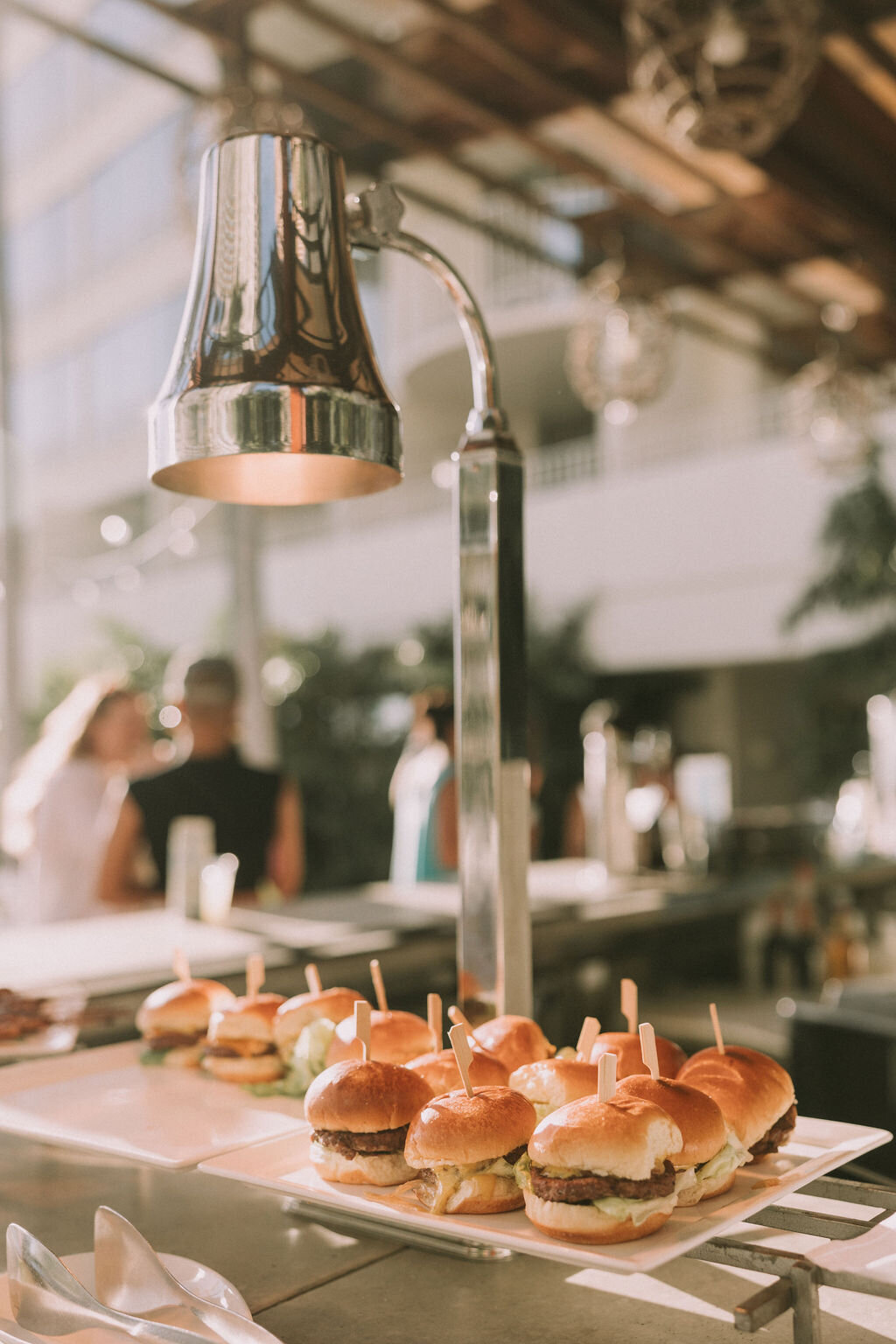 mini hamburgers on a tray with a heating lamp