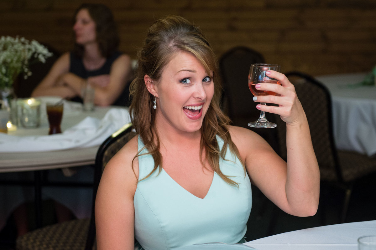 bridesmaid holds up wine glass to photographer
