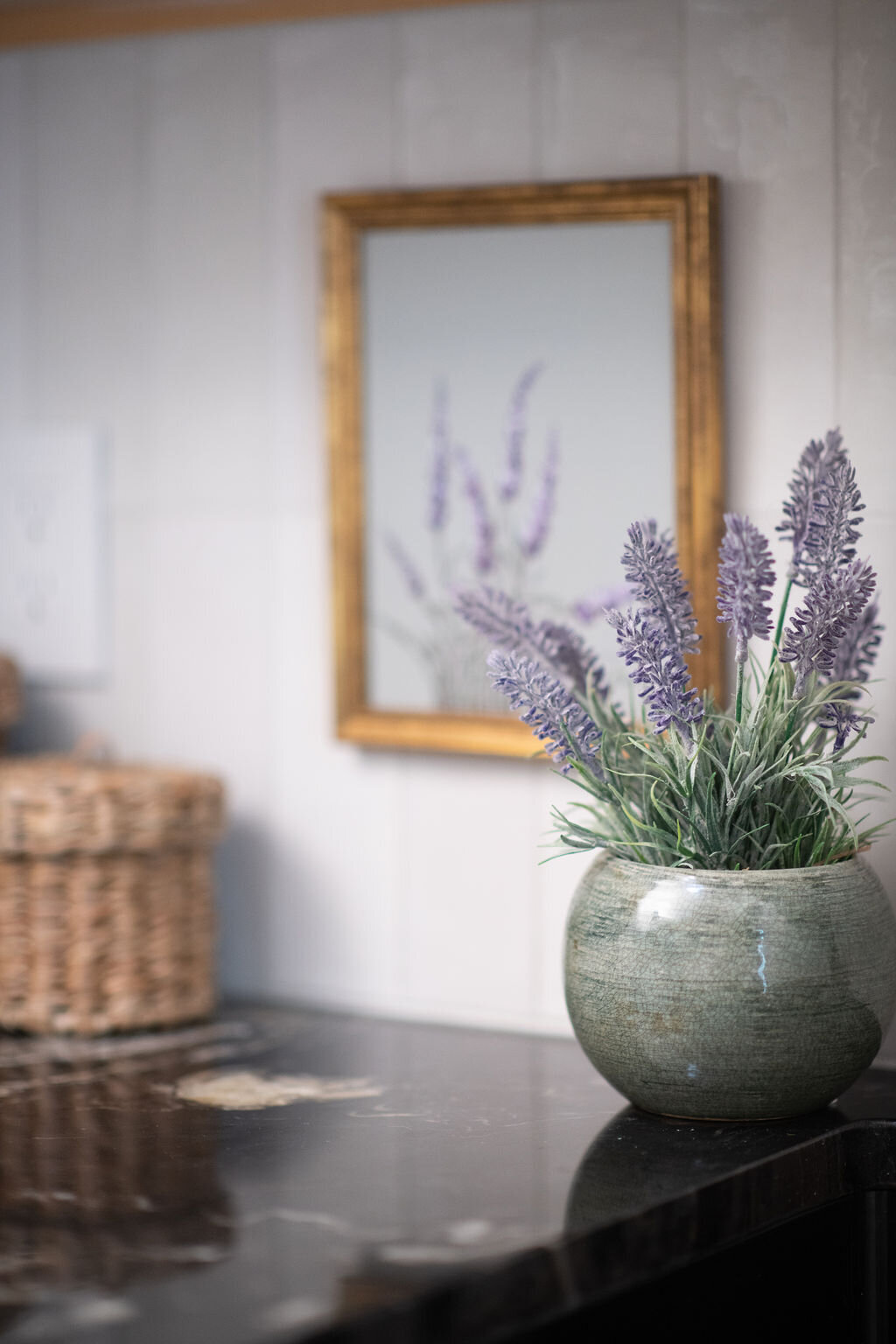 a pot with lavender in it sitting on a counter with lavender artwork in the background