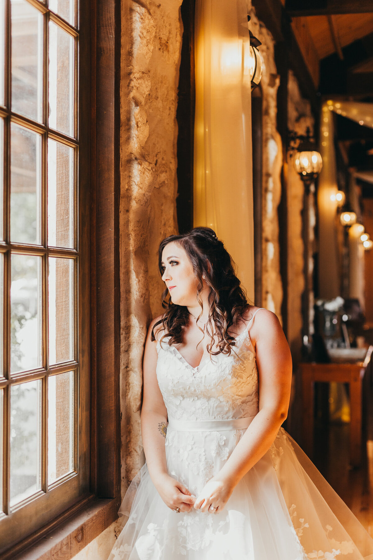 bride stands against a window in her wedding gown at venue in angleton texas
