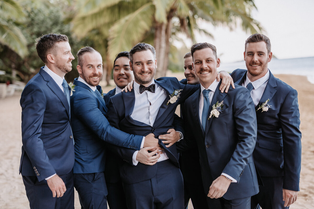 Groosmen portrait hugging wearing navy blue suits on the beach