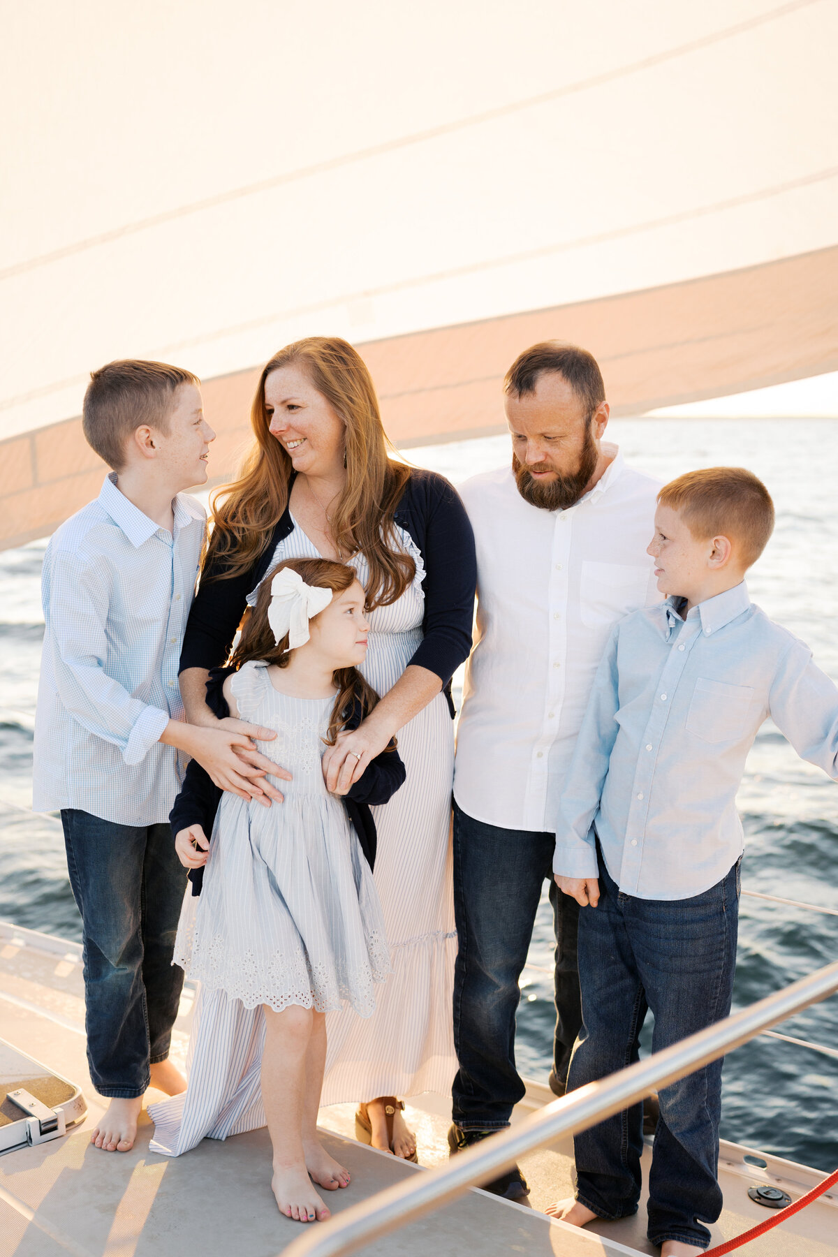 Mom and dad smiling at children on a sailboat in Virginia Beach Family Photography session