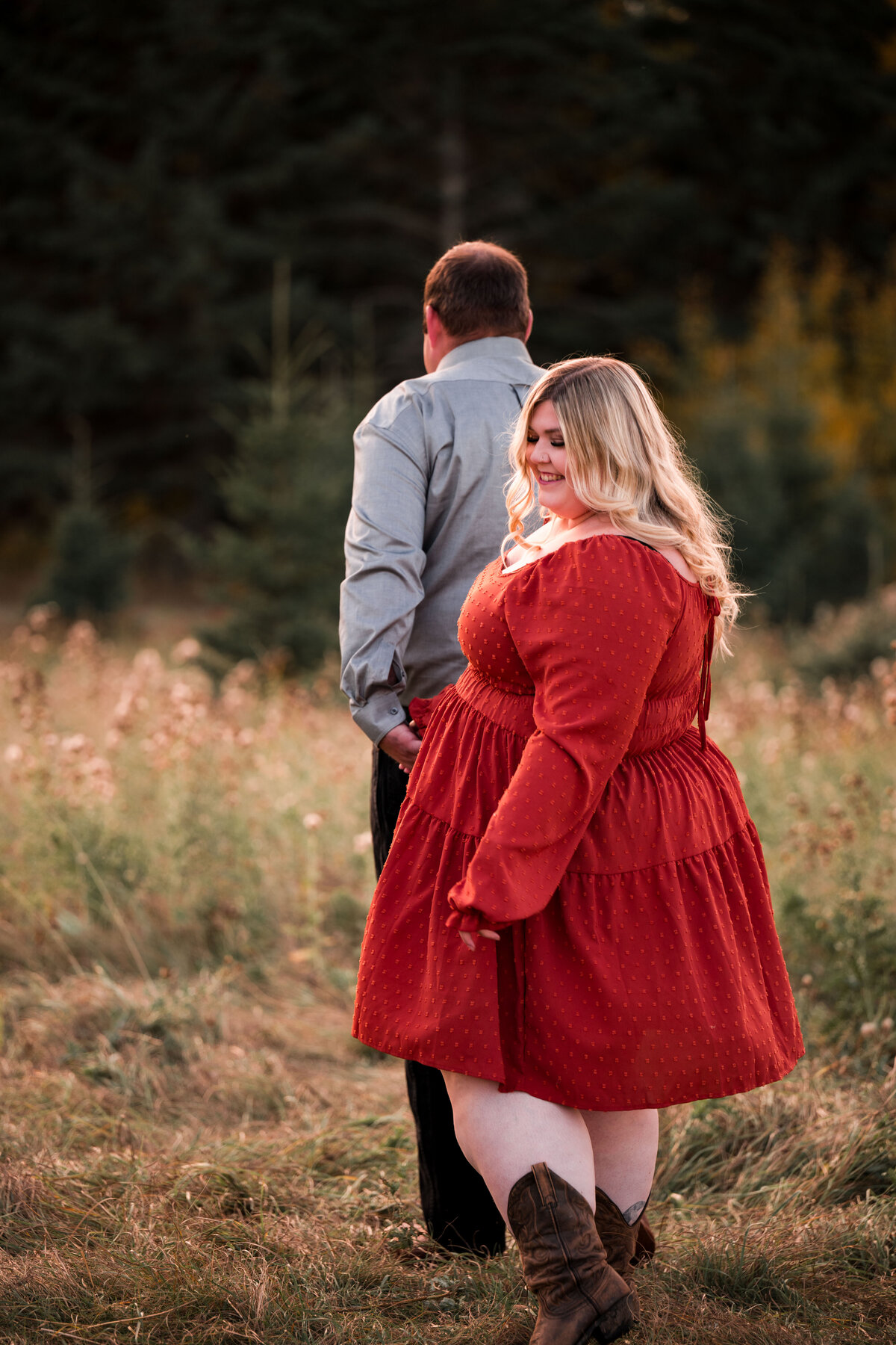 man leads woman through a field in the fall