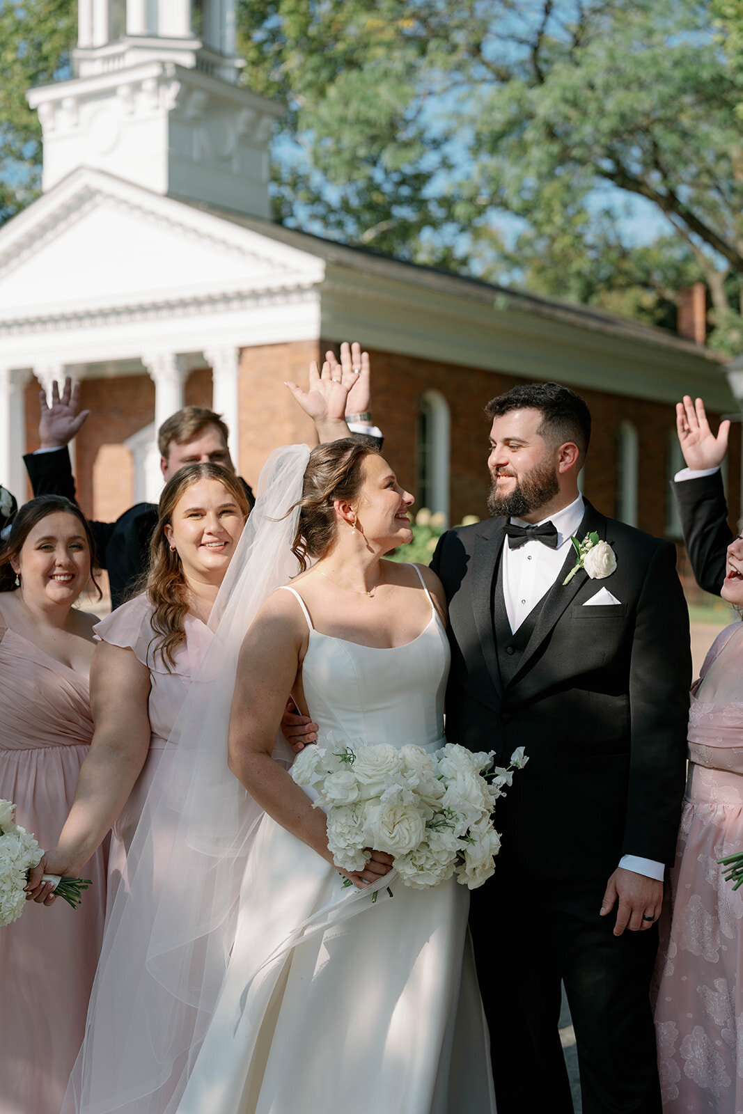 Full wedding party walking together outside Martha-Mary Chapel in Dearborn Michigan, joyful candid bridal party moment.