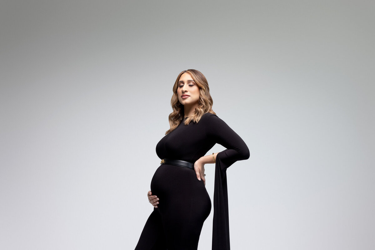 A woman with one hand on her back and the other under her baby bump