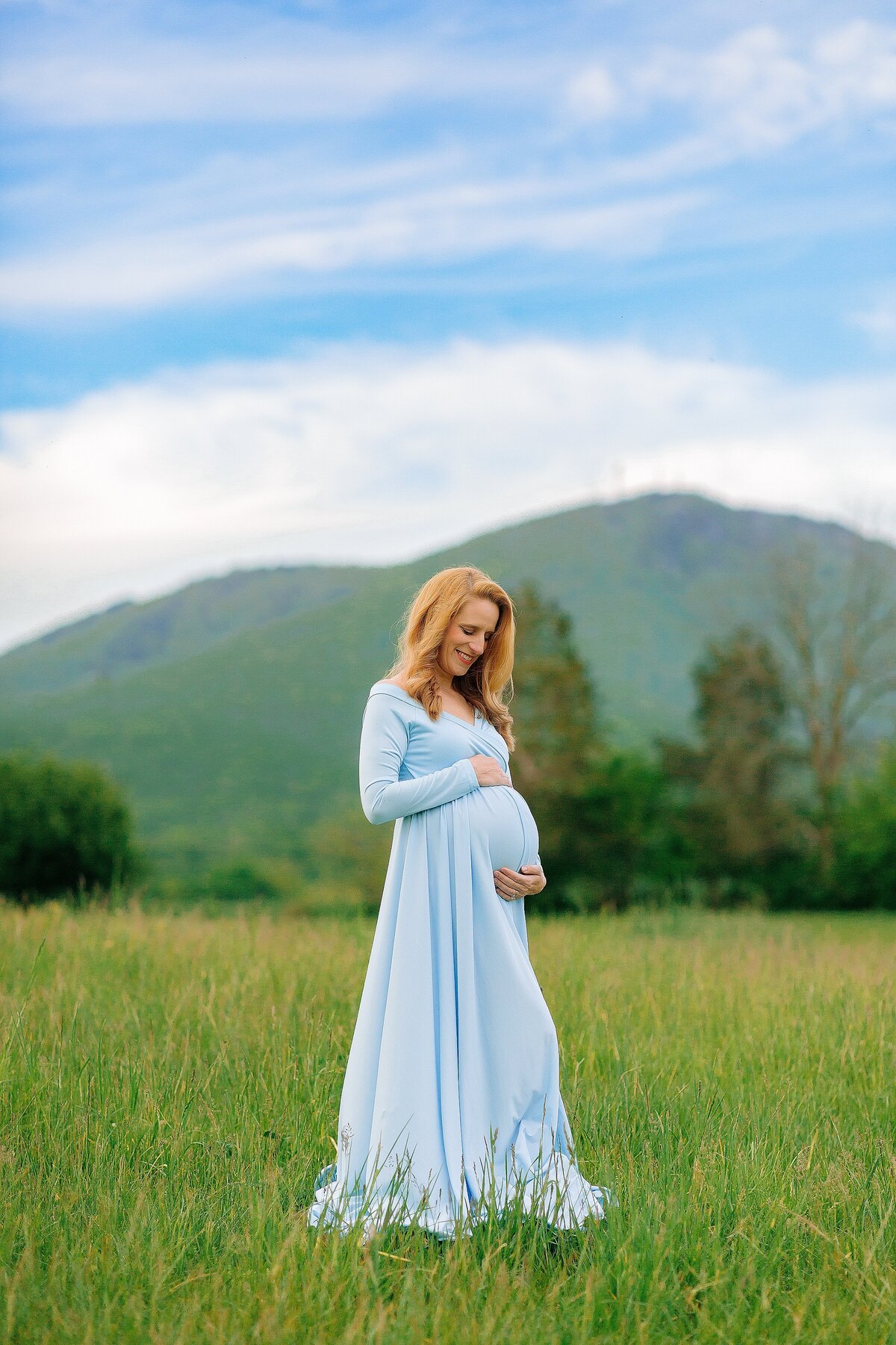 Mom to be wearing blue dress with mountains in the background