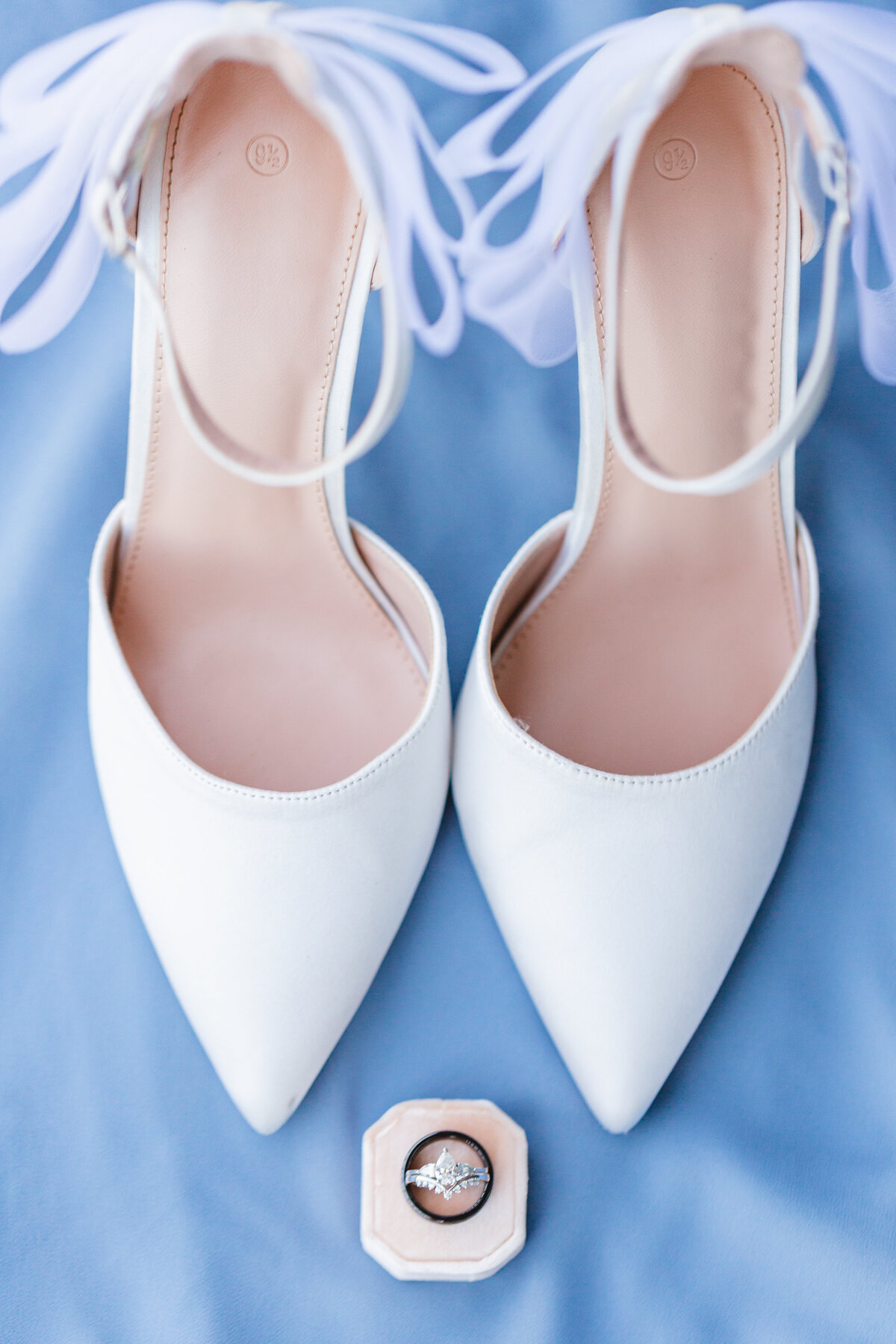 white bride shoes with wedding rings on a blue background