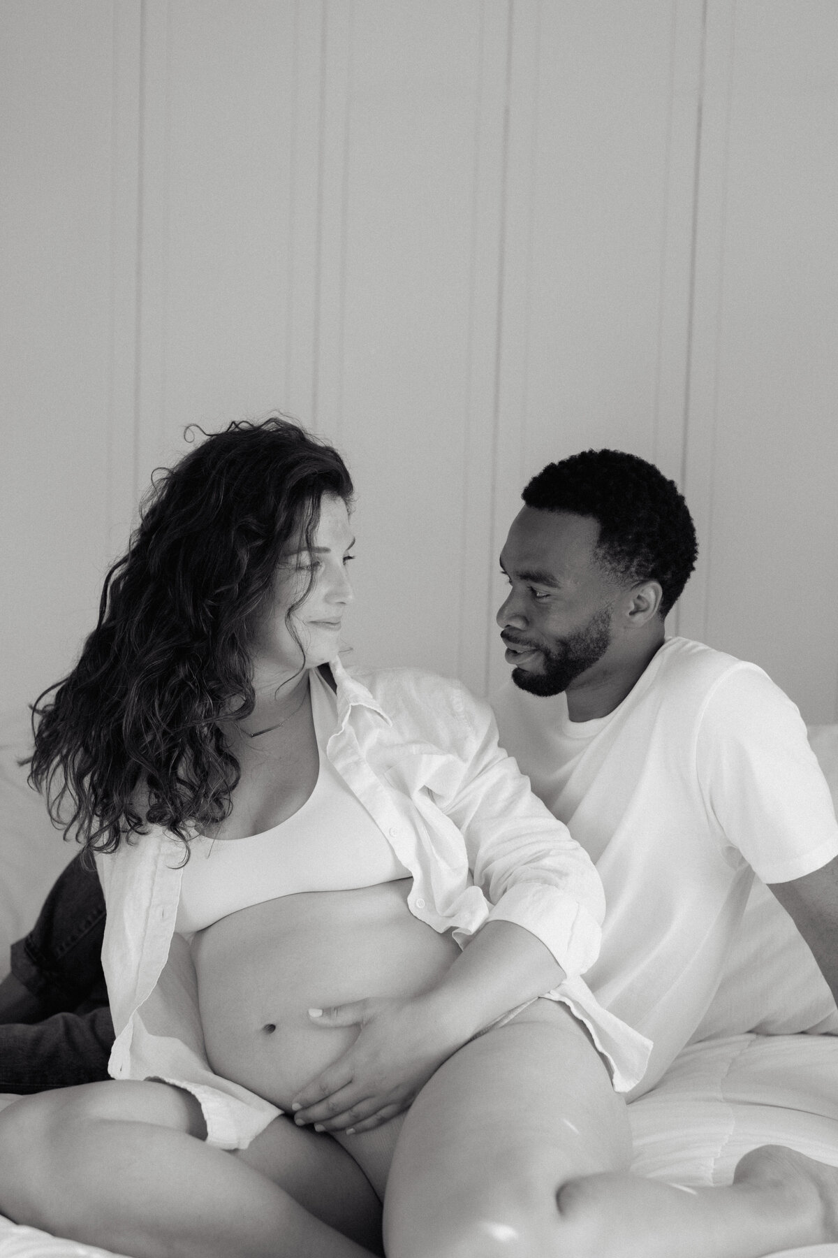 A mother-to-be reclining in a softly lit setting, photographed with an editorial wedding photographer’s touch.