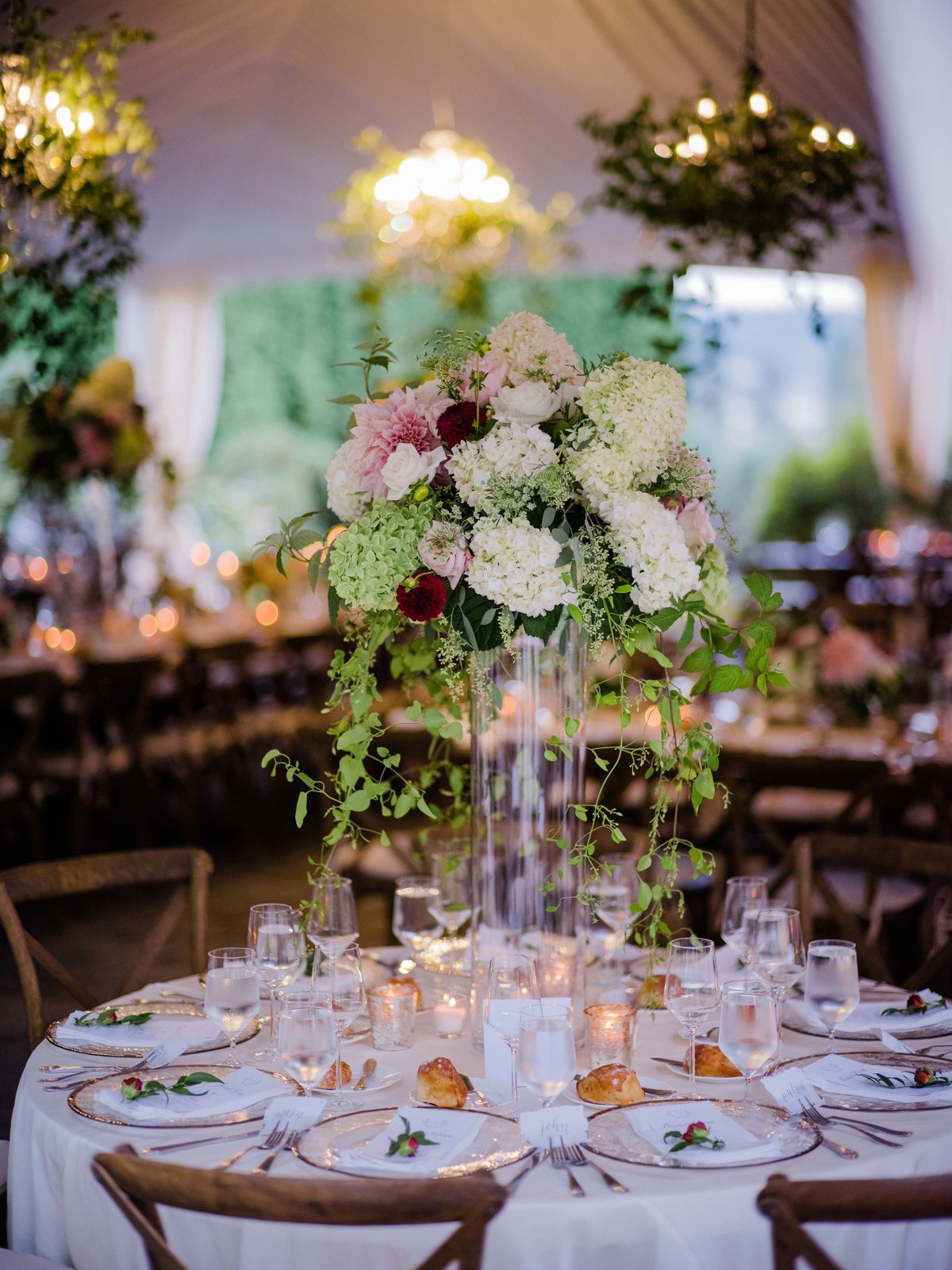 Romantic loose garden style tall vase arrangements look perfect in this tent wedding reception.