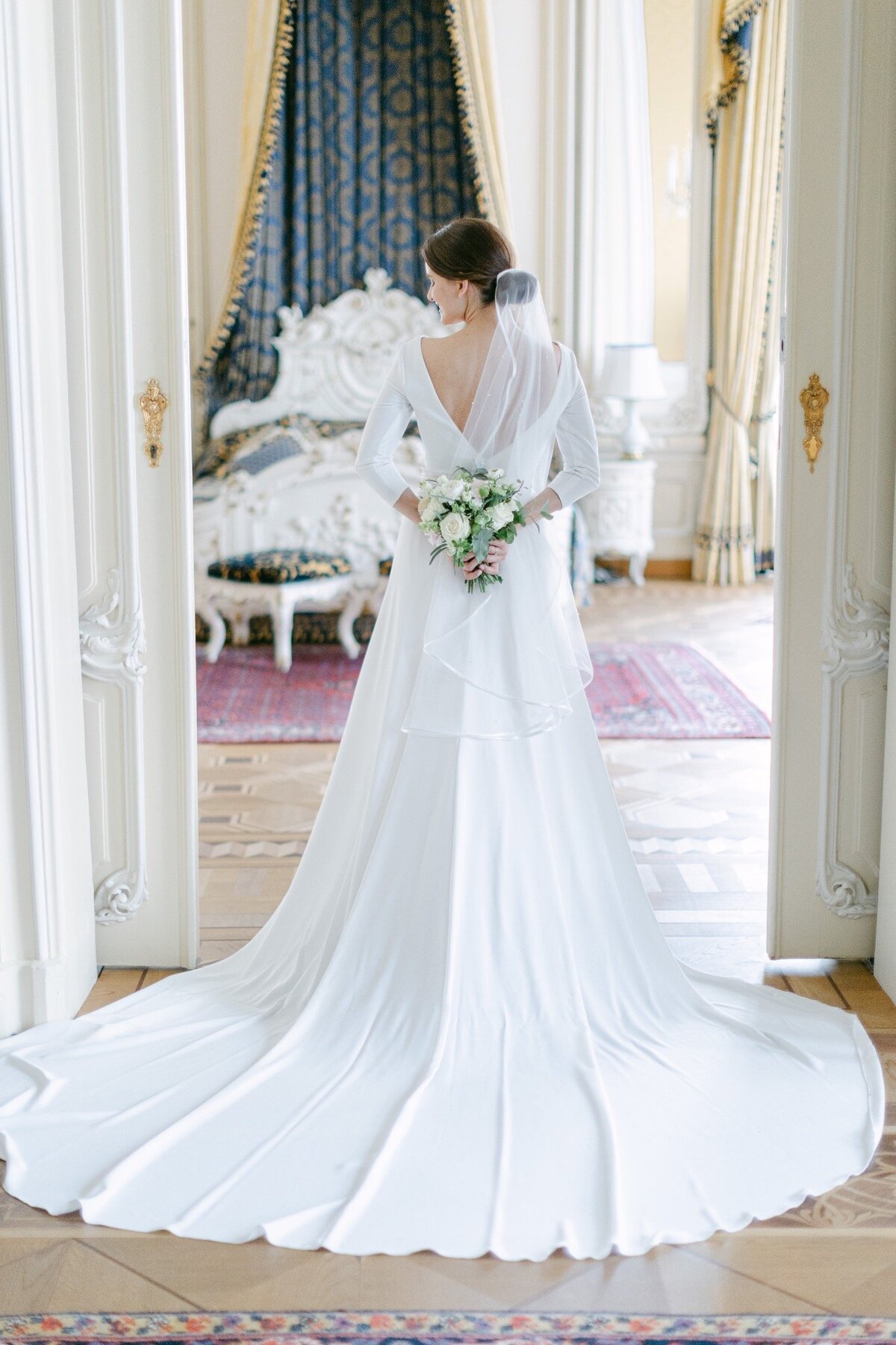 Luxury destination wedding bride standing in the door holding her flower bouquet at the luxury Imperial Hotel in Vienna