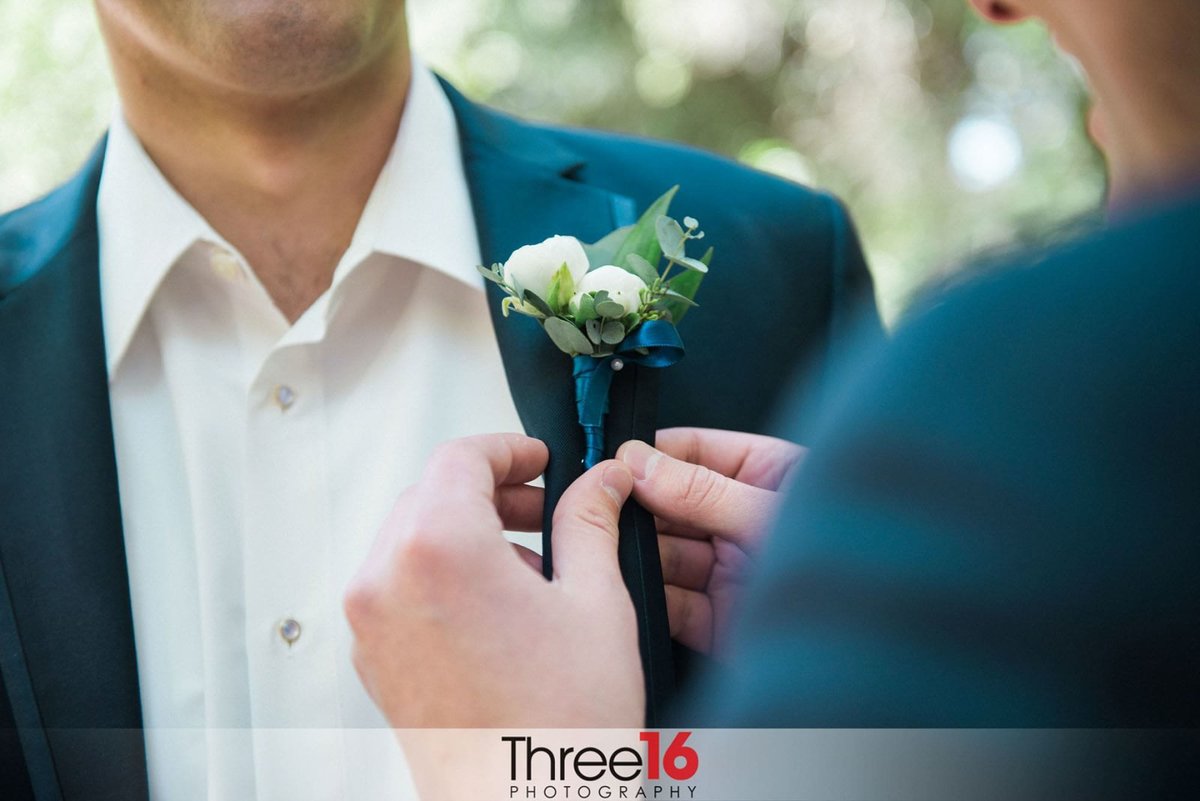 Groom having his boutonniere put on