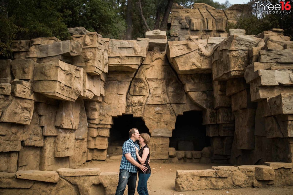Groom to be kisses his fiance's forehead during photo session at the old LA Zoo in Griffith Park