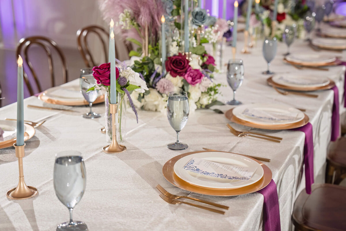 Elegant table setting with rich floral arrangements at a high-end wedding reception.