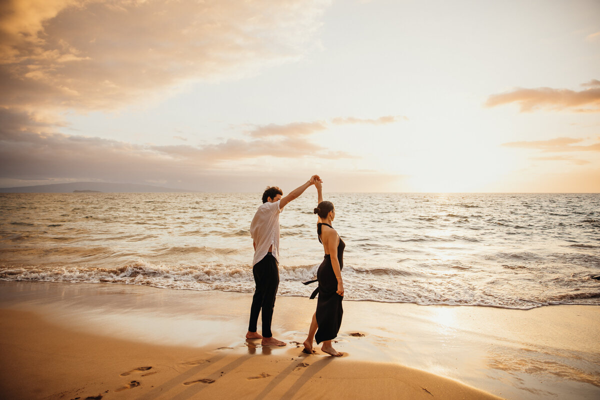 Hawaii Engagement Photographer captures sunset beach engagement photos while man spins woman