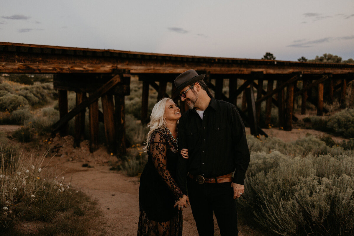 newly weds walking along  a wooden train bridge in Santa Fe