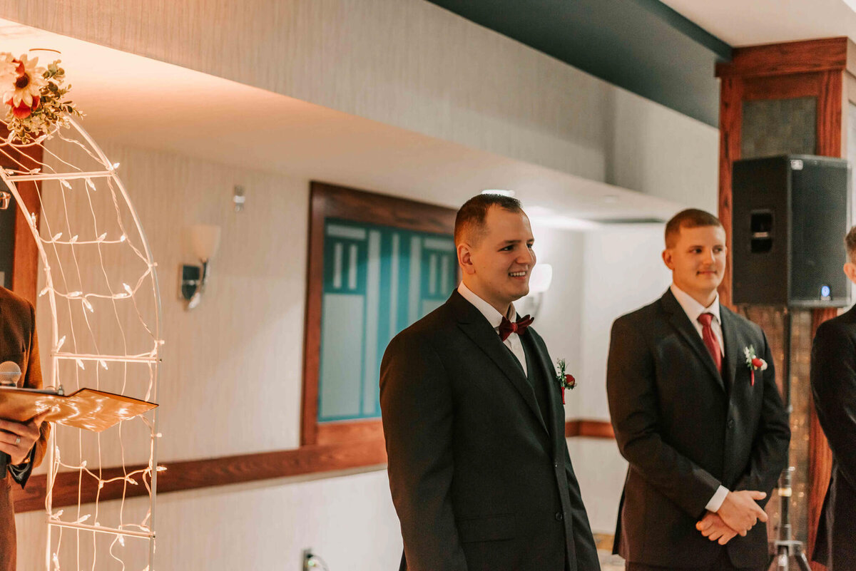 Groom looking at his bride coming down the aisle.