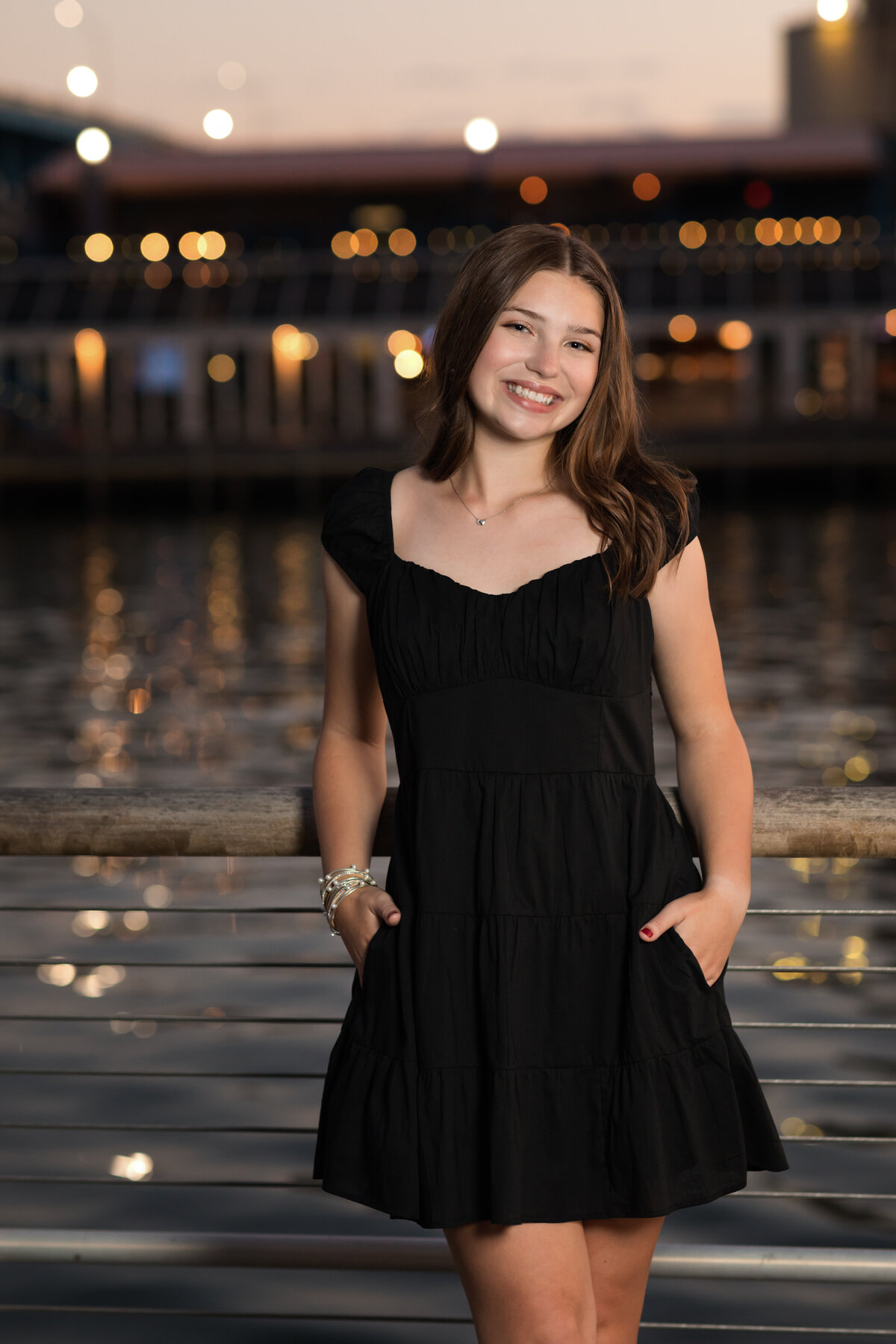 senior girl in black dress posed by water in cleveland for senior portraits